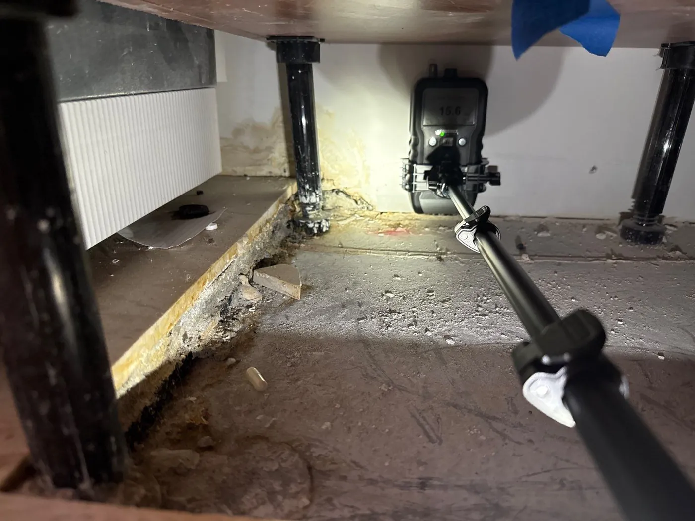 Moisture meter reading beneath a cabinet during a Riviera Beach, FL mold inspection